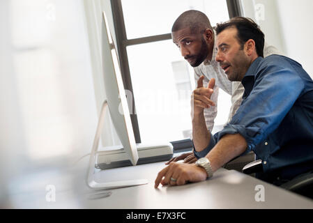 Büroalltag. Zwei Männer an einem Schreibtisch, einen Computer zu betrachten. Stockfoto