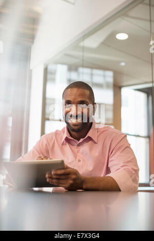 Büroalltag. Ein Mann sitzt an einem Schreibtisch mit einem Laptopcomputer. Stockfoto