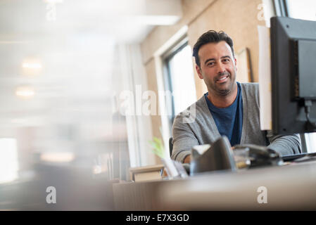 Büroalltag. Ein Mann sitzt an einem Schreibtisch mit einem Computer. Stockfoto