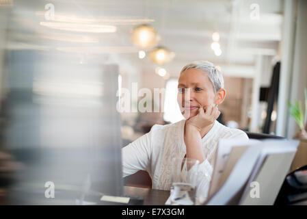 Büroalltag. Eine Frau mit ihrem Kinn auf ihre Hand mit Hilfe eines Computers. Stockfoto