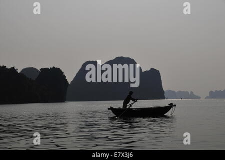 Ha Long Bucht, Vietnam. 24. Sep, 2014. --Ein Fischerboot segelt durch Wasserwege zwischen den Inseln und Inselchen in der untergehenden Sonne in Ha Long Bay, Nordvietnam, 24. September 2014. Ha Long Bay, im Golf von Tonkin, enthält einige 1.600 Inseln und Inselchen, bilden eine spektakuläre Seenlandschaft von Kalksteinsäulen. Aufgrund ihrer schroffen Natur sind die meisten Inseln unbewohnt und unberührt von menschlicher Anwesenheit. Herausragende landschaftliche Schönheit des Aufstellungsortes wird durch seine große biologische Interesse ergänzt. Es war im Jahr 1994 eingeschriebenen im UNESCO Weltnaturerbe-Liste. (Xinhua/Zhang Jianhua) Stockfoto