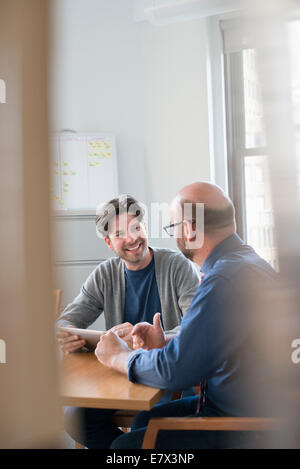Zwei Kollegen im Büro sprechen und unter Bezugnahme auf eine digital-Tablette. Stockfoto
