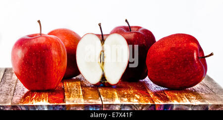 Vier rote Äpfel und einen halben Apfel auf Holzbrett Stockfoto