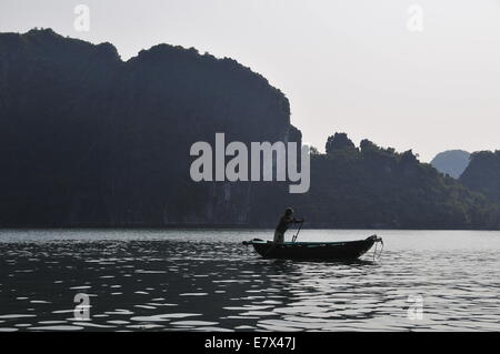 (140925)--HA LONG BAY, 25. September 2014 (Xinhua)--ein Fischerboot segelt durch Wasserwege zwischen den Inseln und Inselchen in der untergehenden Sonne in Ha Long Bay, Nordvietnam, 24. September 2014. Ha Long Bay, im Golf von Tonkin, enthält einige 1.600 Inseln und Inselchen, bilden eine spektakuläre Seenlandschaft von Kalksteinsäulen. Aufgrund ihrer schroffen Natur sind die meisten Inseln unbewohnt und unberührt von menschlicher Anwesenheit. Herausragende landschaftliche Schönheit des Aufstellungsortes wird durch seine große biologische Interesse ergänzt. Es war im Jahr 1994 eingeschriebenen im UNESCO Weltnaturerbe-Liste. (Xinhua/Zhang Jianhua) Stockfoto