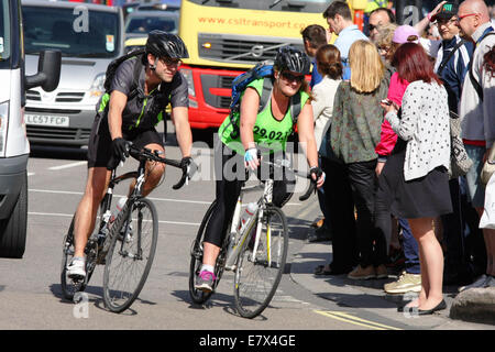 Zwei Radfahrer fahren um eine Ecke in London als Fußgänger die Straße überqueren warten Stockfoto