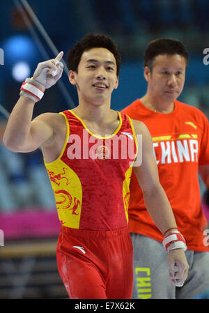 (140925)--INCHEON, 25. September 2014 (Xinhua)--Zou Kai (L) von China feiert nach die Männer Reck-Finale der Gymnastik künstlerisches Ereignis bei den 17. Asian Games in Incheon, Südkorea, 25. September 2014. Zou Kai gewann die Goldmedaille mit 15,800 Punkten.  (Xinhua/Zhu Zheng) (Mcg) Stockfoto