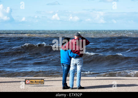 Junges Paar Arm in Arm und Blick auf Meer Stockfoto