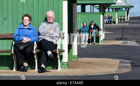 Ältere Paare sitzen auf Bänken in einer Reihe von Unterkünften auf der Promenade in Blackpool Stockfoto