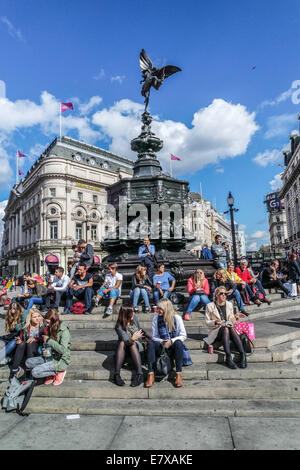 Piccadilly Circus, London, Touristen sitzen auf den Stufen des Eros-Statue Stockfoto