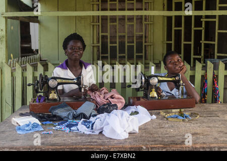 Frauen, die Herstellung von Kleidern mit Nähmaschinen auf der Veranda ihres Hauses in ghana Stockfoto