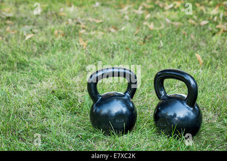 zwei schwere Eisen Kettlebells auf einem Rasen - Hinterhof-Fitness-Konzept Stockfoto