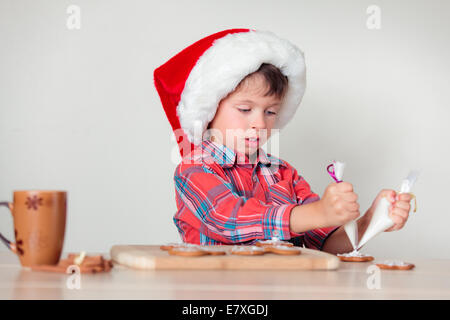 Niedliche kleine Junge verzieren Lebkuchen, Frohe Weihnachten Stockfoto