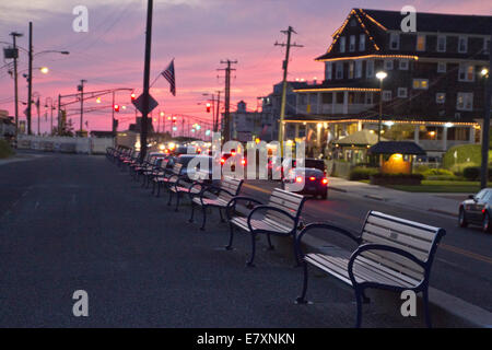 Blick auf den Bänken entlang der Zement Gehweg grenzt an den Strand in Cape May, New Jersey bei Sonnenuntergang Stockfoto