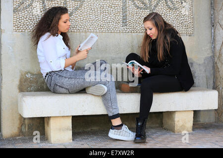Zwei Freundinnen, Teenager, sitzen auf einer Steinbank, Lesebücher, Menton, Alpes-Maritimes, Provence-Alpes, Frankreich Stockfoto