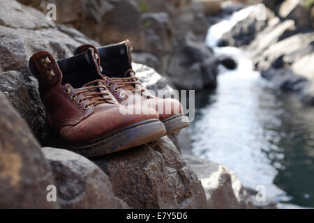 Begrenzten Fokus Wanderschuhen auf Felsen mit unscharfen Fluss, Bach, Wasserfall bei Lotheni, Drakensburg, Südafrika Stockfoto