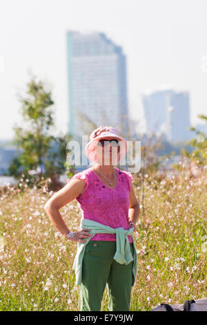 Frau in Greenwich mit hoch aufragenden Gebäude in der Ferne in London im September Stockfoto