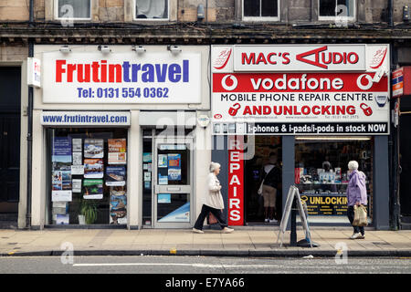 Zwei Frauen zu Fuß vorbei an lokalen Unternehmen in Leith, Edinburgh Stockfoto