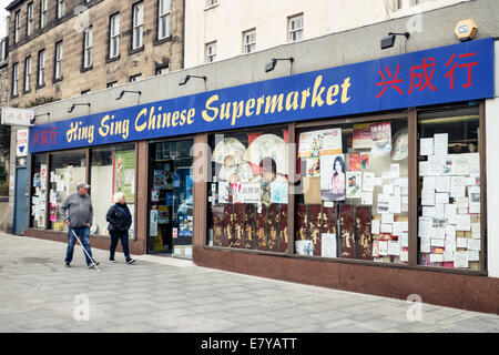 Zwei Menschen, die zu Fuß vorbei an einen chinesischen Supermarkt auf Leith Walk, Edinburgh Stockfoto