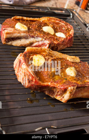 Nahaufnahme von zwei rohe Steaks mariniert mit Öl und Knoblauch auf Grill Stockfoto