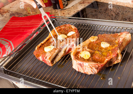 Nahaufnahme von zwei rohe Steaks mariniert mit Öl und Knoblauch auf Grill Stockfoto