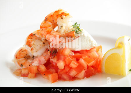 Frische und leckere Garnelen mit Zitrone und Tomate auf weiße Schale Stockfoto