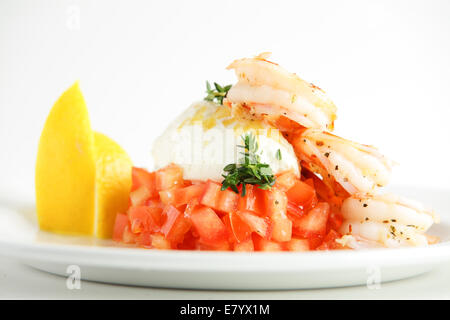 Frische und leckere Garnelen mit Zitrone und Tomate auf weiße Schale Stockfoto