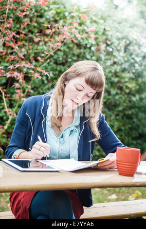 Frau sitzt im Freien mit TabletPC Stockfoto