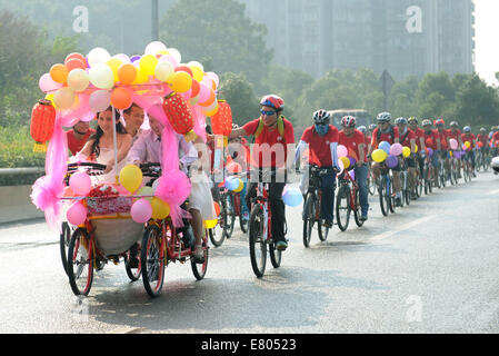 Der Provinz Hunan Changsha, China. 27. Sep, 2014. Jiang Yan Braut und Bräutigam Huang Bo Fahrrad ein Vierrad Hochzeit in Changsha, der Hauptstadt der Provinz Zentral-China Hunan, 27. September 2014. Das Paar, zusammen mit ihren Kumpels Reiten feierten ihre Hochzeit von Fahrrad am Samstag. Bildnachweis: Li Ga/Xinhua/Alamy Live-Nachrichten Stockfoto