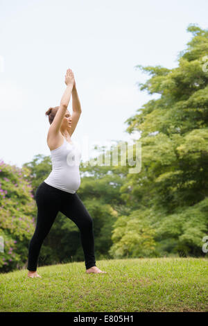 Schwangere Frau beim Yoga im park Stockfoto