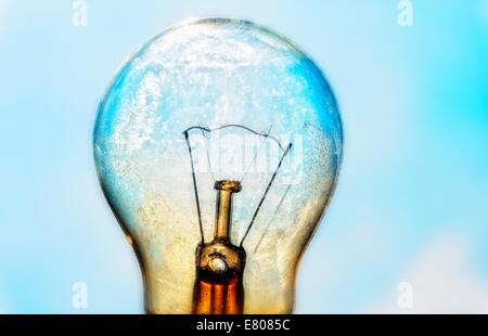Aufnahme einer Glühbirne mit einem gebrochenen Filament vor einem sonnigen blauen Himmel hautnah Stockfoto