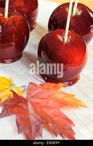 Die rote Toffee Äpfel für Halloween Süßes oder Saures essen Süßigkeiten, auf Backpapier und Backrost mit Herbst Herbst Blatt Stockfoto