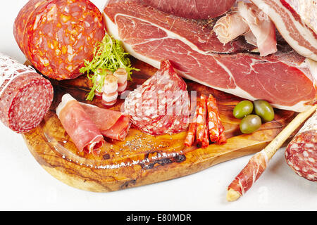 Holzbrett mit verschiedenen Arten von Fleisch auf weißem Hintergrund Stockfoto
