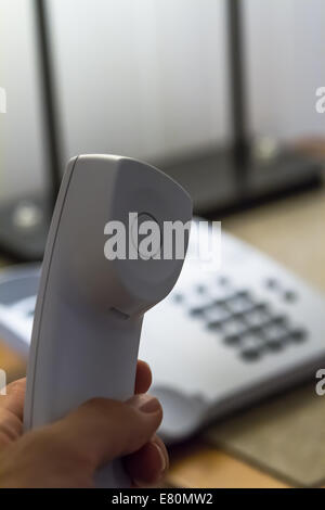 Hand, die weißes Telefon Rohr im Hotelzimmer. Stockfoto