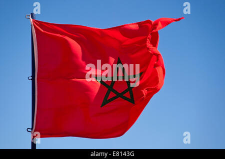 Horizontale Nahaufnahme der Nationalflagge Marokkos vor blauem Himmel. Stockfoto