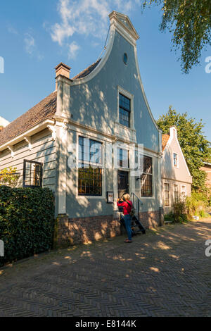 Frau, die ein Foto eines historischen Hauses in 'Broek in Waterland', Nord Holland, Niederlande. Stockfoto