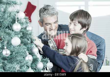 Vater mit Sohn und Tochter Weihnachtsbaum zu verzieren. Weihnachten-Familienkonzept. Stockfoto