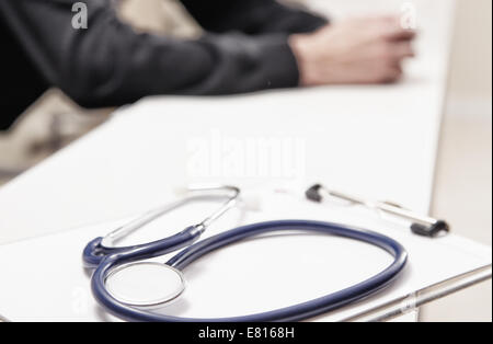 Stethoskop auf dem Schreibtisch mit Arzt im Hintergrund. Stockfoto