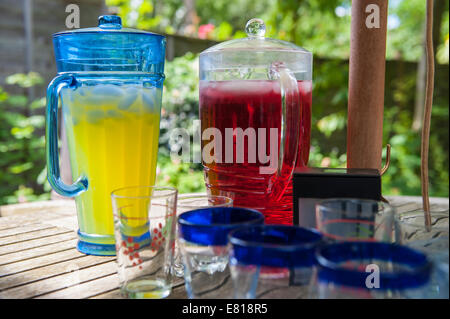 Zwei Krüge mit Squash und einige Gläser an einem heißen Sommertag im Garten für einige Kinder zum trinken Stockfoto