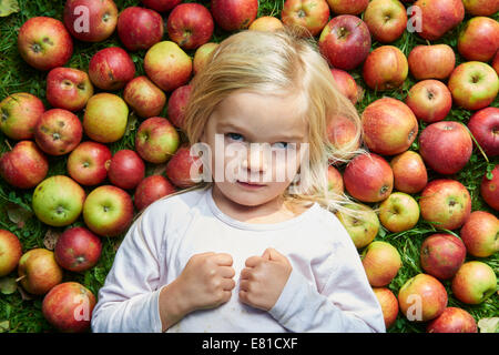 kleines Mädchen auf dem Rasen liegend mit grün rote Äpfel Stockfoto