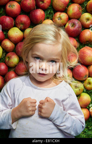 kleines Mädchen auf dem Rasen liegend mit grün rote Äpfel Stockfoto