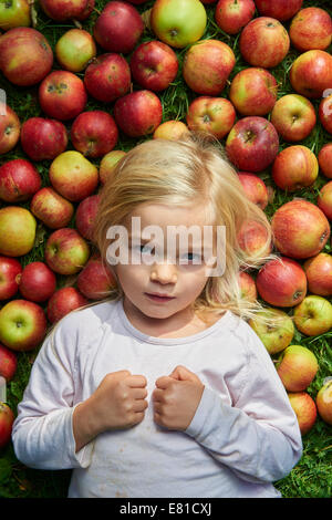 kleines Mädchen auf dem Rasen liegend mit grün rote Äpfel Stockfoto