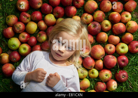 kleines Mädchen auf dem Rasen liegend mit grün rote Äpfel Stockfoto