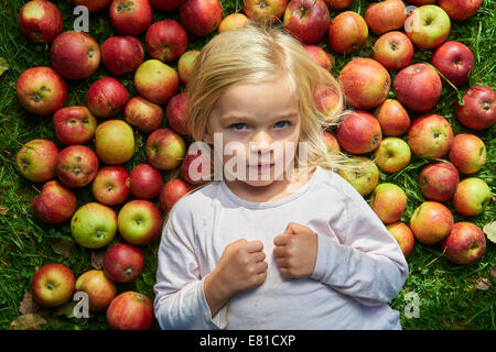 kleines Mädchen auf dem Rasen liegend mit grün rote Äpfel Stockfoto