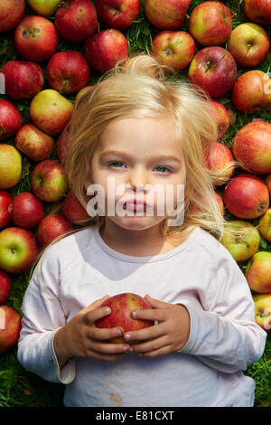 kleines Mädchen auf dem Rasen liegend mit grün rote Äpfel Stockfoto