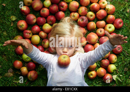 kleines Mädchen auf dem Rasen liegend mit grün rote Äpfel Stockfoto