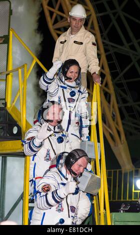 Internationale Raumstation ISS-Expedition 41 Besatzungsmitglieder, Alexander Samokutyaev von der russischen Federal Space Agency, unten, Astronaut Barry Wilmore der NASA, Center und Elena Serova Welle vor dem Einsteigen in das Raumschiff Sojus TMA - 14 M für den Start zur internationalen Raumstation ISS 25. September 2014 in Baikonur, Kasachstan. Samokutyaev, Serova und Wilmore verbringen die nächsten fünfeinhalb Monate Leben und arbeiten an Bord der ISS. Stockfoto