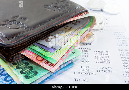 Brieftasche und Geld in verschiedene Banknoten und Münzen mit Kreditkartenabrechnung als Hintergrund Stockfoto