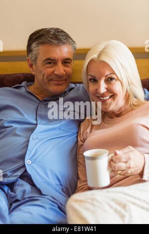 Gerne älteres paar lächelnd in die Kamera auf Bett Stockfoto
