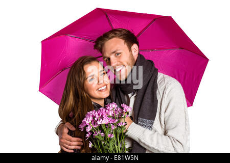 Fröhliches junges Paar mit Blumen und Sonnenschirm Stockfoto