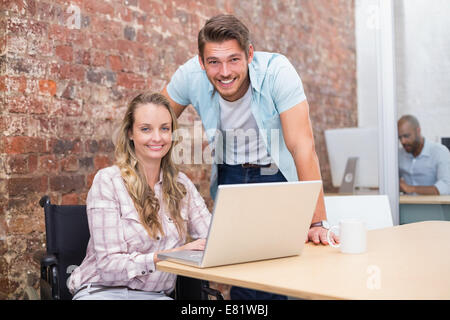 Lächelnde Geschäftsfrau im Rollstuhl, die Zusammenarbeit mit Kollegen Stockfoto